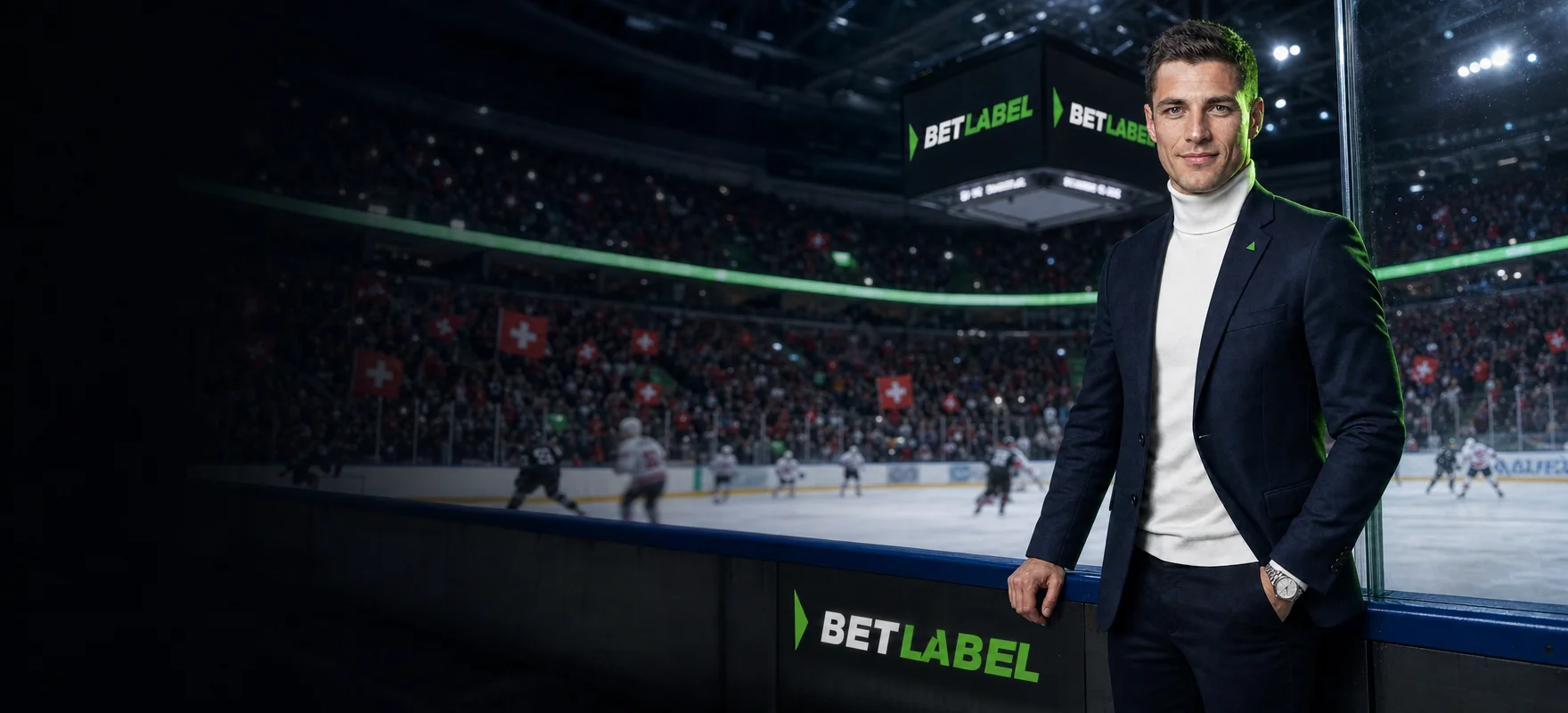 Mann im mitternachtsblauen Blazer am Spielfeldrand einer Eishockey-Arena, auf den LED-Banden das BetLabel-Logo